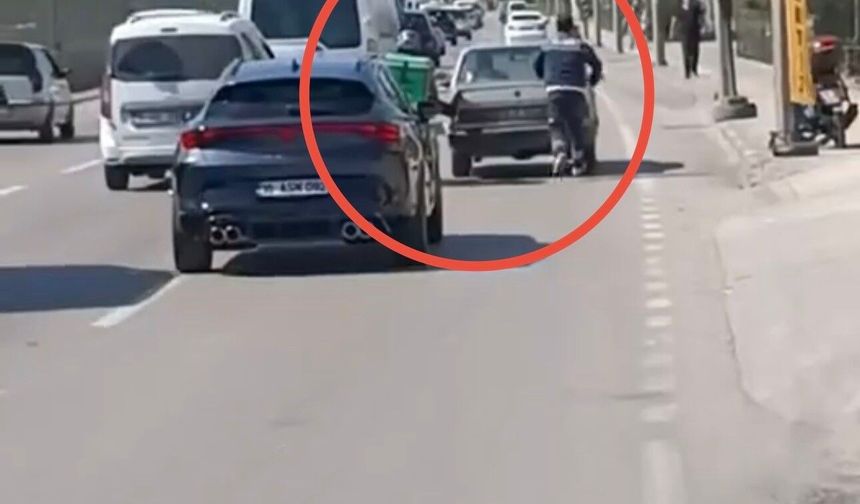 Bursa'da motokuryeden arızalanan otomobili itmek için ilginç yöntem